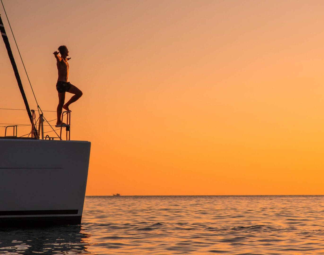 A man standing on the side of a boat in the ocean.