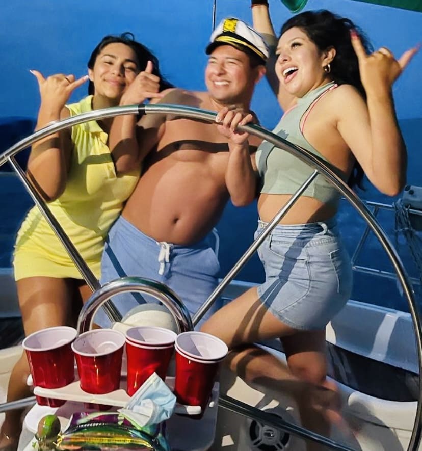 A group of people on a boat with drinks.