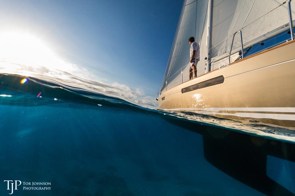 A man standing on the bow of a boat in the ocean.