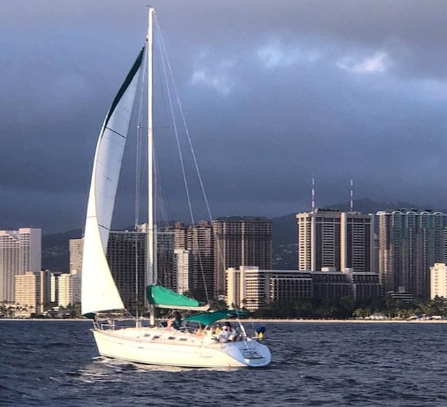 A sailboat in the ocean with a city skyline behind it.