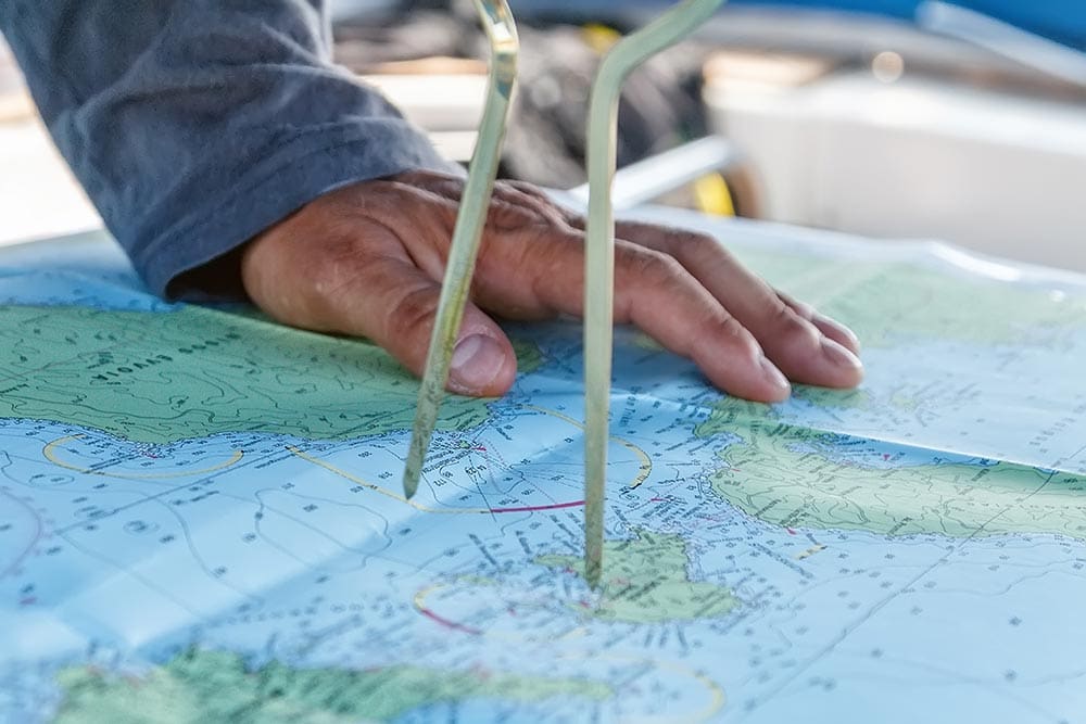 A person holding two straws over a map.