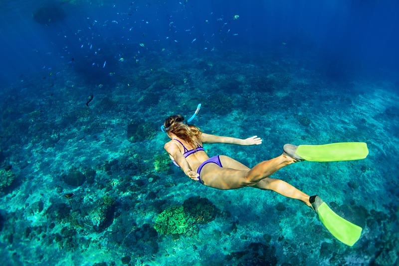 A woman swimming in the ocean with flippers.