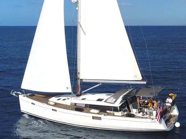 A white sailboat with two people on it.