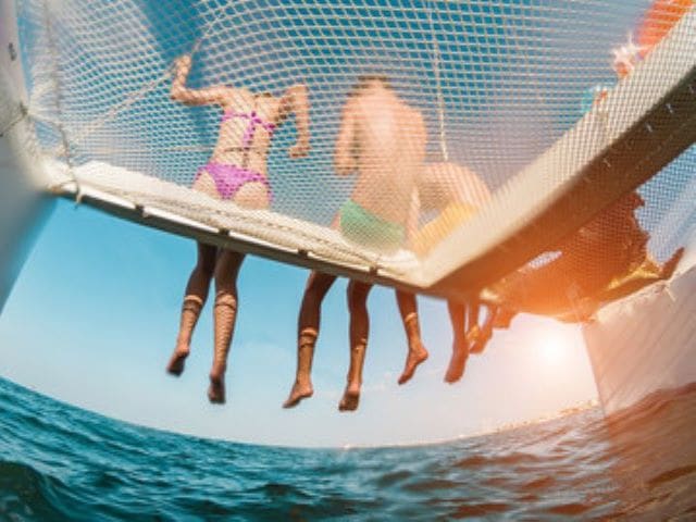 A group of people hanging on to the side of a boat.