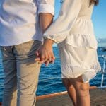 A man and woman holding hands on the deck of a boat.