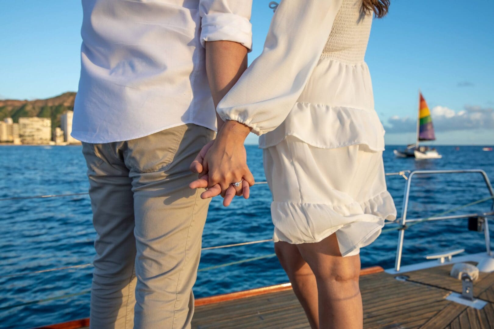 A man and woman holding hands on the deck of a boat.